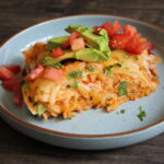 Slice of chorizo and egg enchilada with avocado and diced tomato