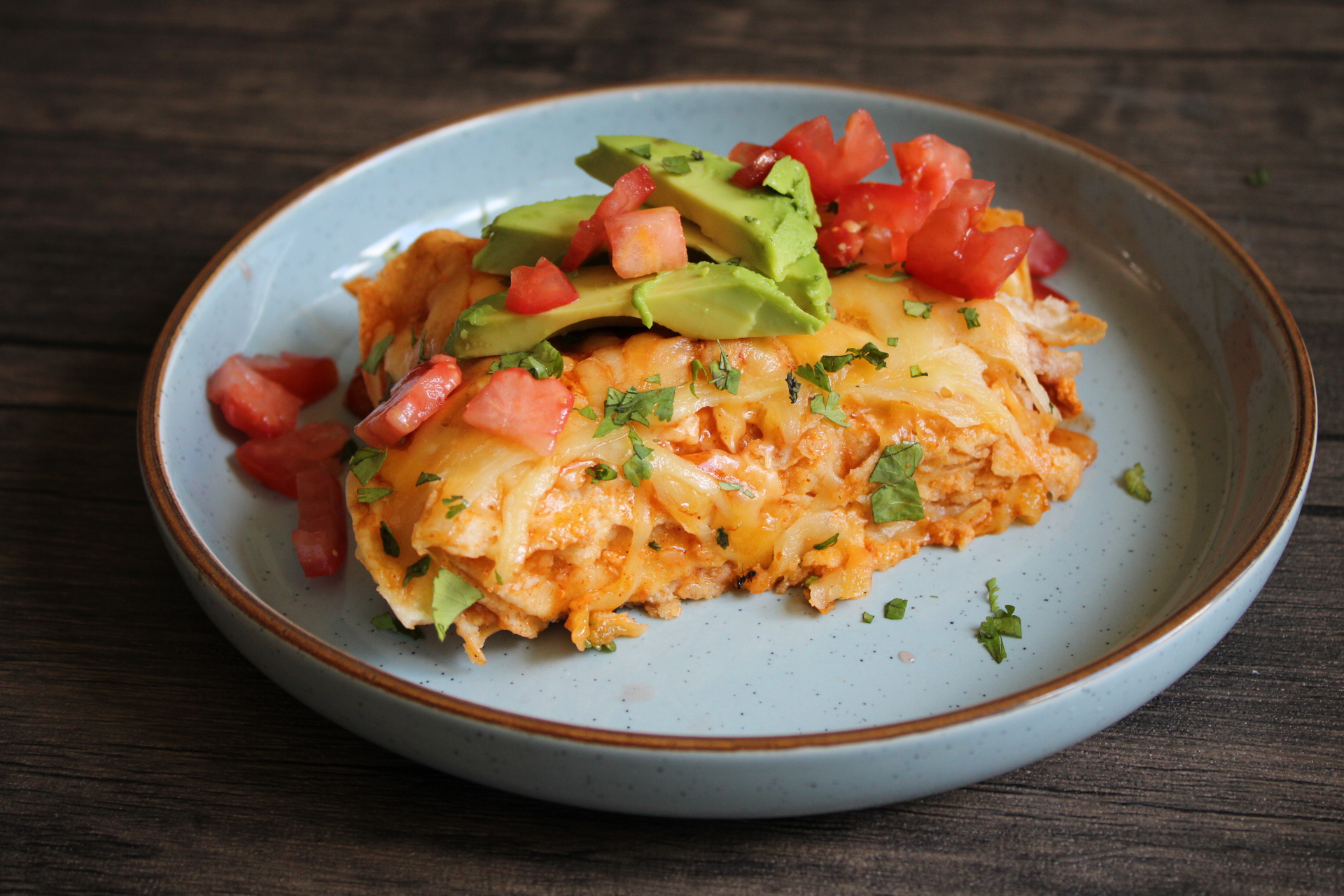 Slice of chorizo and egg enchilada with avocado and diced tomato