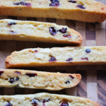 Multiple cranberry orange biscotti arranged on a wooden cutting board