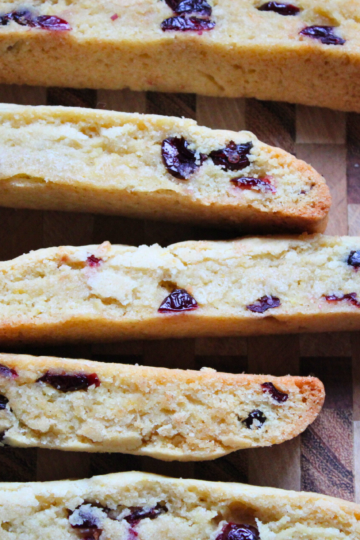 Multiple cranberry orange biscotti arranged on a wooden cutting board