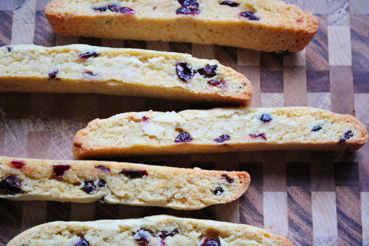 Multiple cranberry orange biscotti arranged on a wooden cutting board