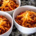 Three bowls of ground beef and macaroni noodles topped with shredded cheese