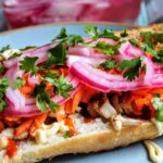 chicken sandwich with orange carrots, red onion and cilantro